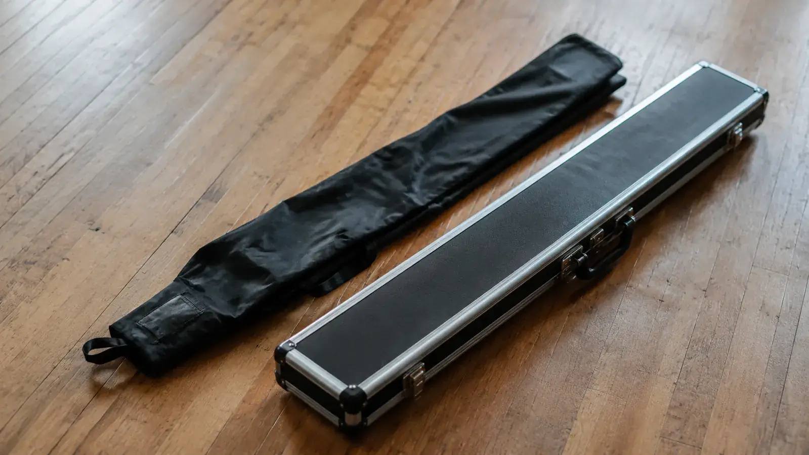 Soft cue bag next to a hard cue case showing the contrast in construction and protection