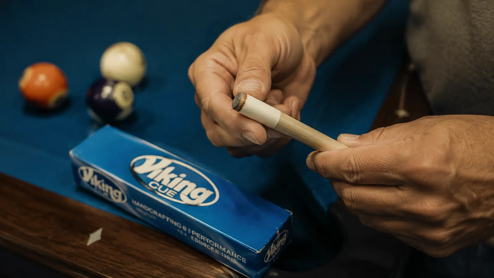 Close-up of a pool cue tip and ferrule being inspected by a player's hand at a billiards table