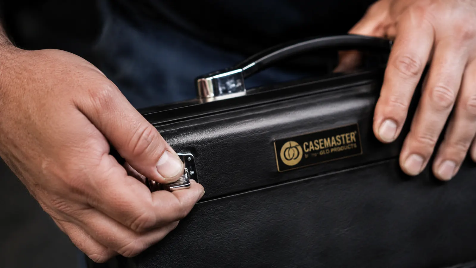 Close-up of a hand pressing down on the Q-Vault Supreme latch mechanism