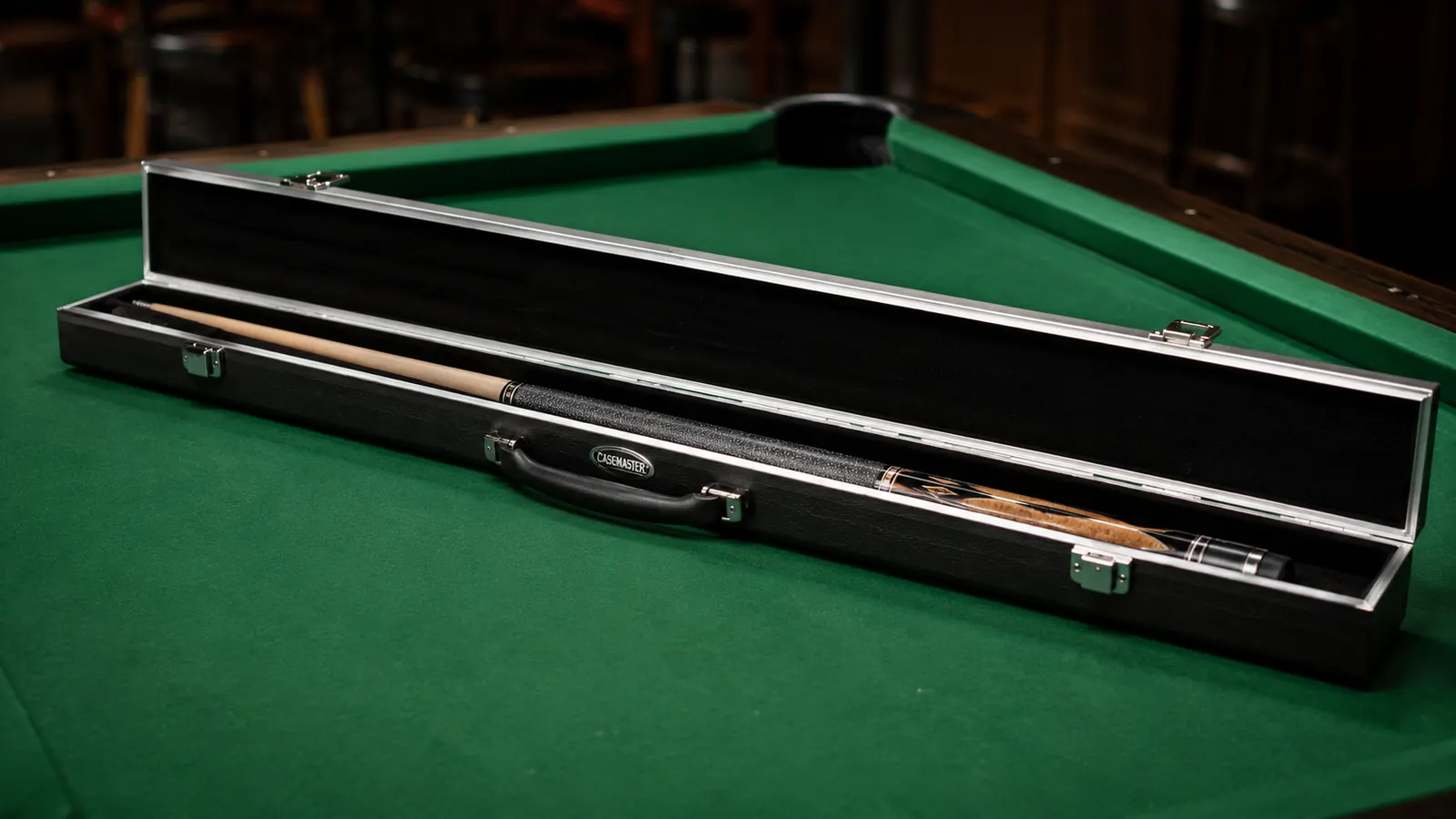 Casemaster Q-Vault case open on a pool table showing two cue sections secured in velvet interior