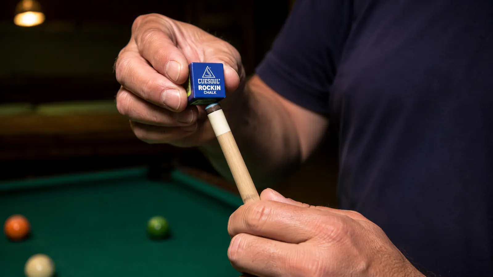 Hand chalking the tip of a CUESOUL Rockin Series cue before a shot