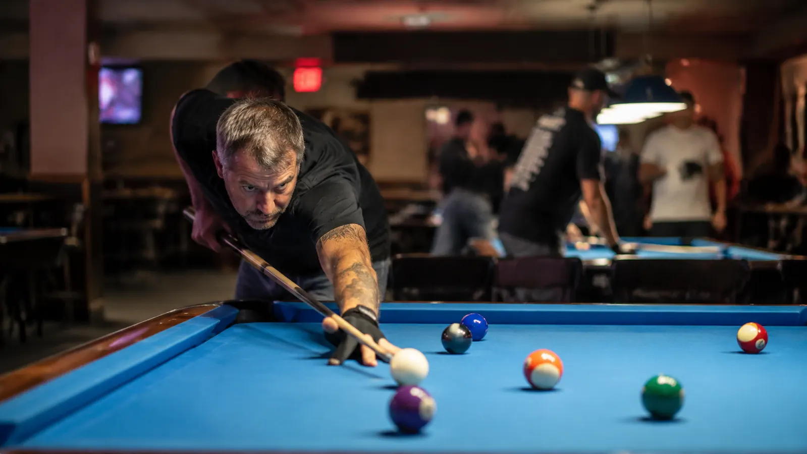 Player lining up a position shot on a pool table in a bar league setting