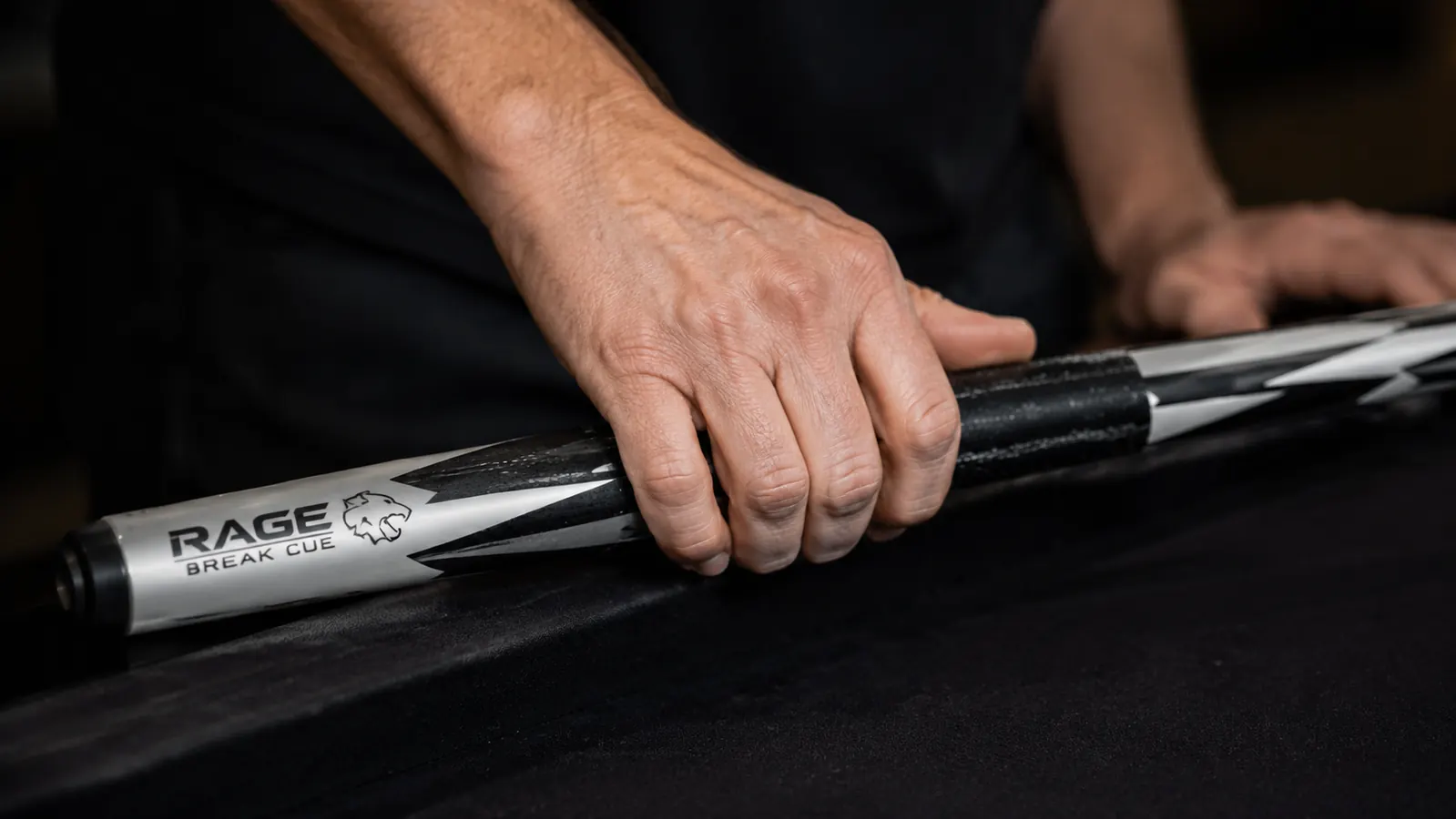 Close-up of a hand gripping a break cue at the wrap point, showing loose finger pressure