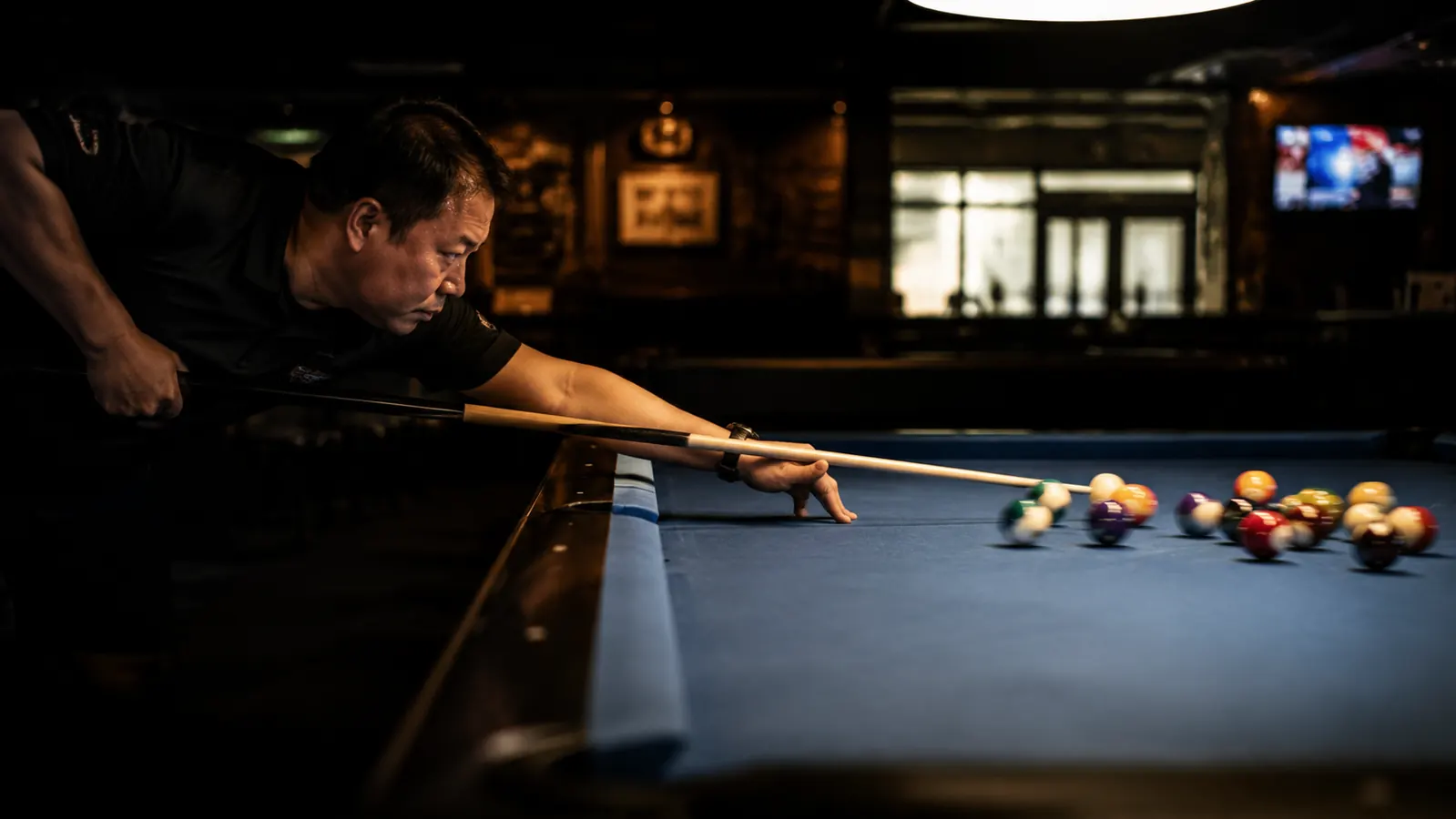 Pool player completing a full follow-through with arm extended straight through the cue ball position