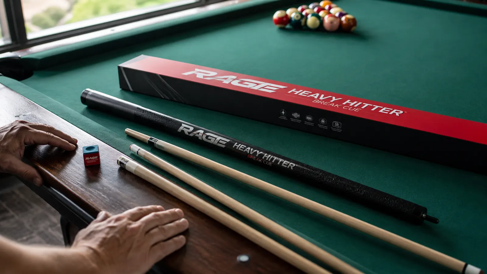 RAGE Heavy Hitter break cue resting on a pool table rail next to a cube of chalk