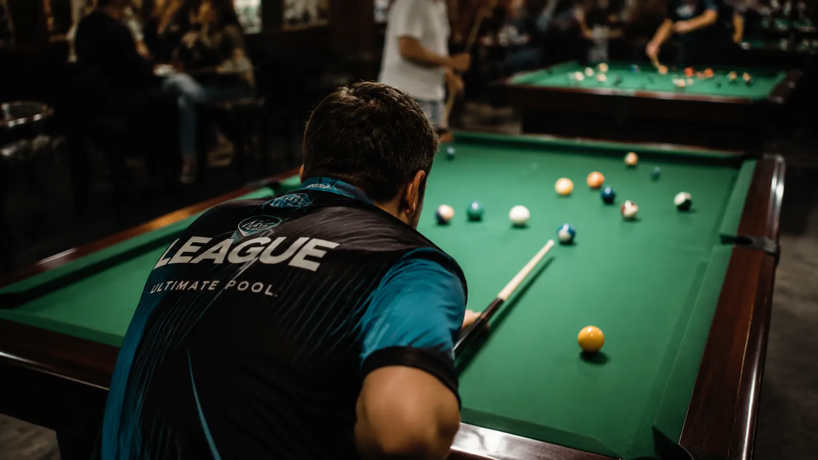 Player leaning on a pool cue with chalk visible on the tip before a shot