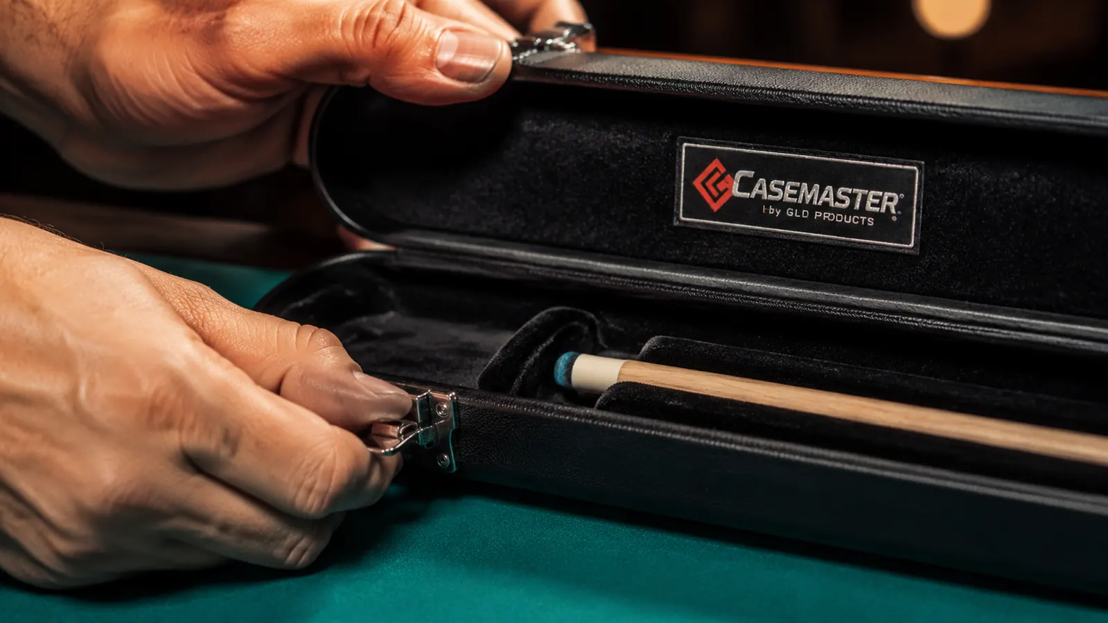 Hand opening the Casemaster Q-Vault Supreme case latch to reveal a two-piece cue secured in velvet interior