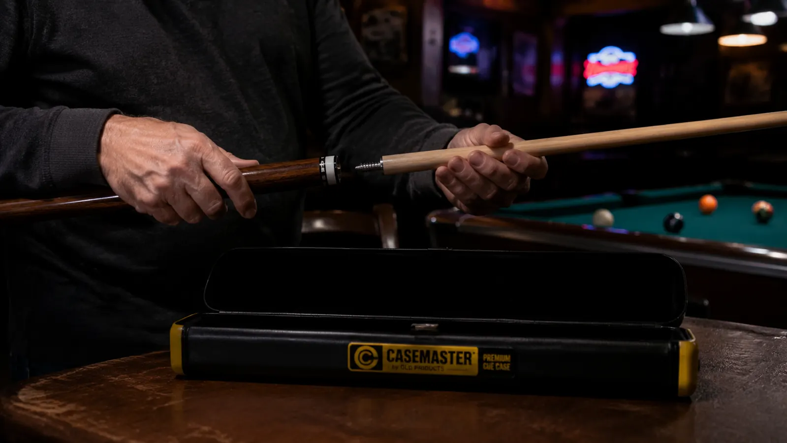 Pool player unscrewing the joint of a two-piece cue and placing each piece into a cue case for transport