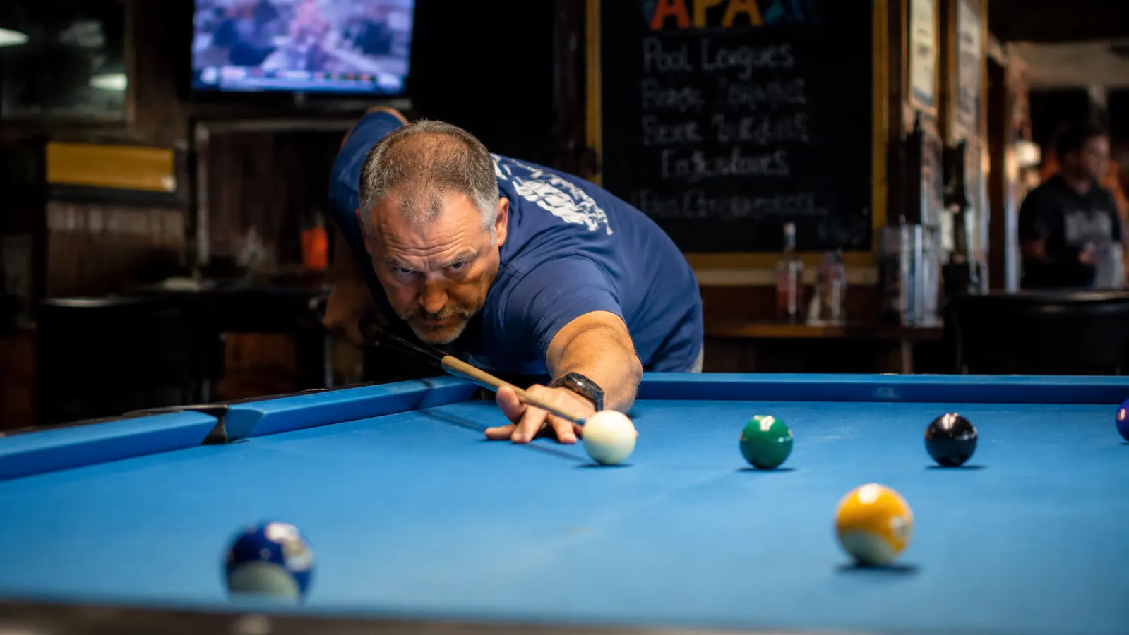 Player lining up a sharp cut shot with heavy side english at a Tuesday night APA league match
