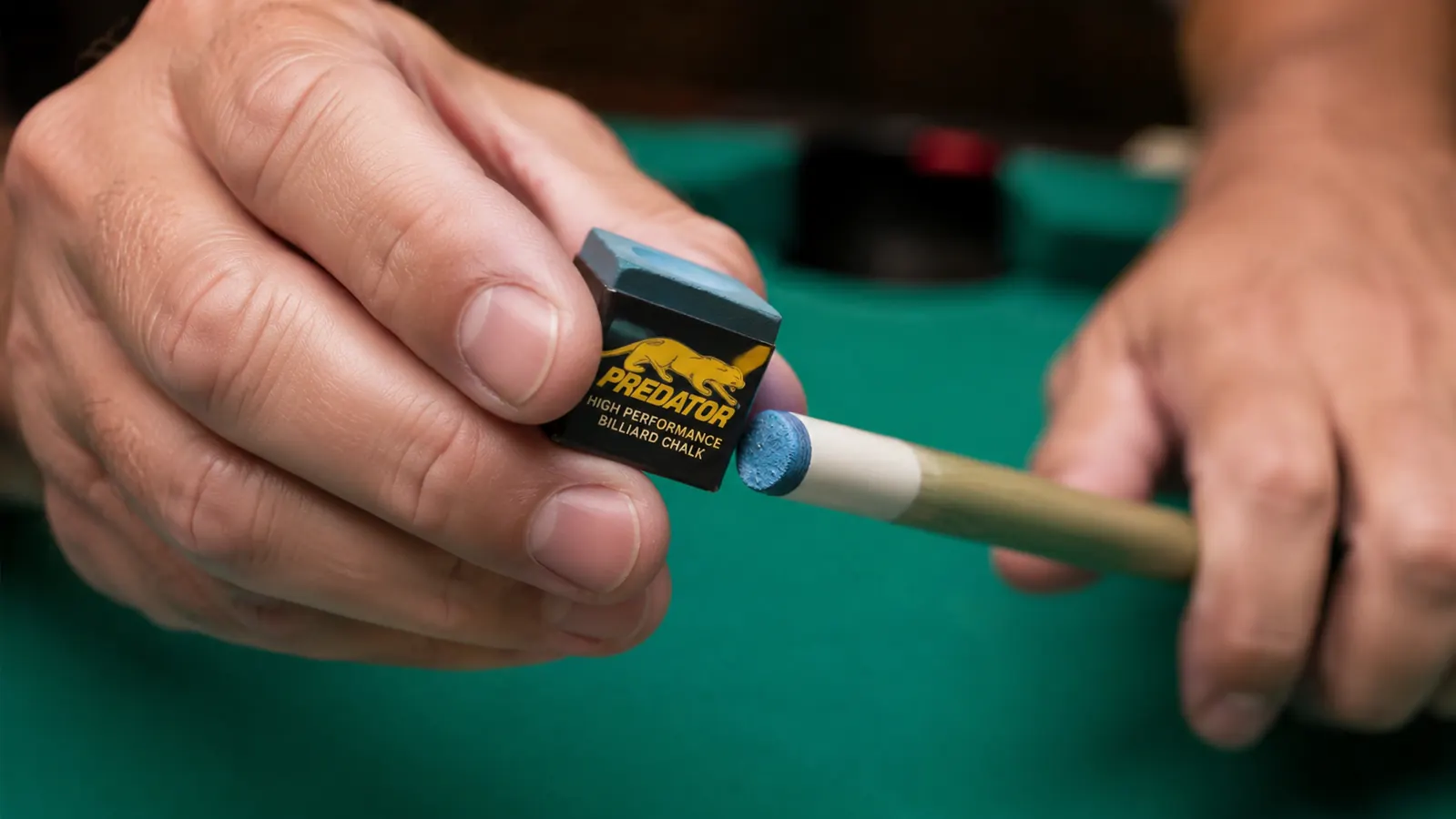 Close-up of a player chalking a pool cue tip with Predator chalk before a shot