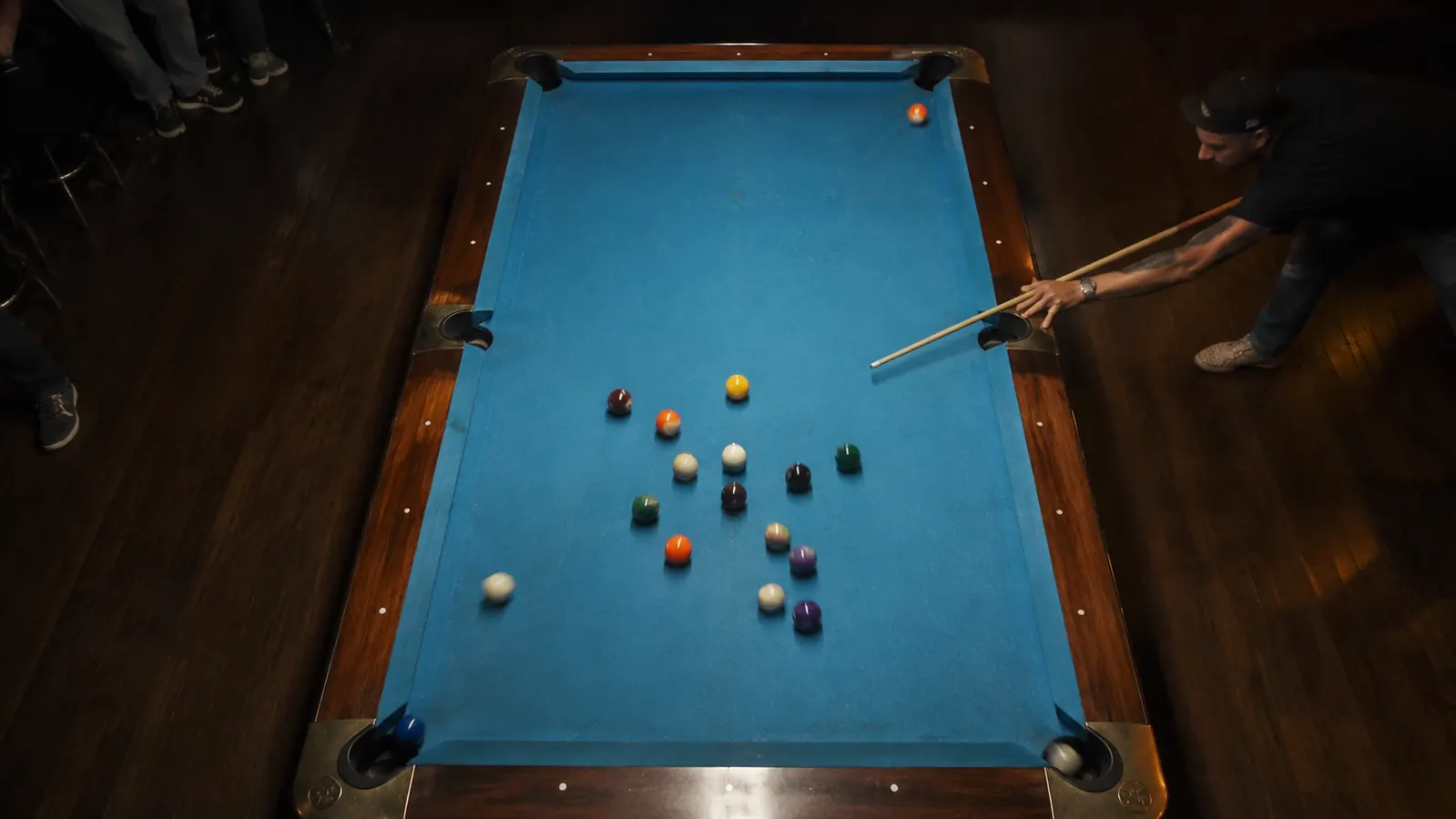 Pool balls scattering on break, shot from above, two balls dropping into corner pockets