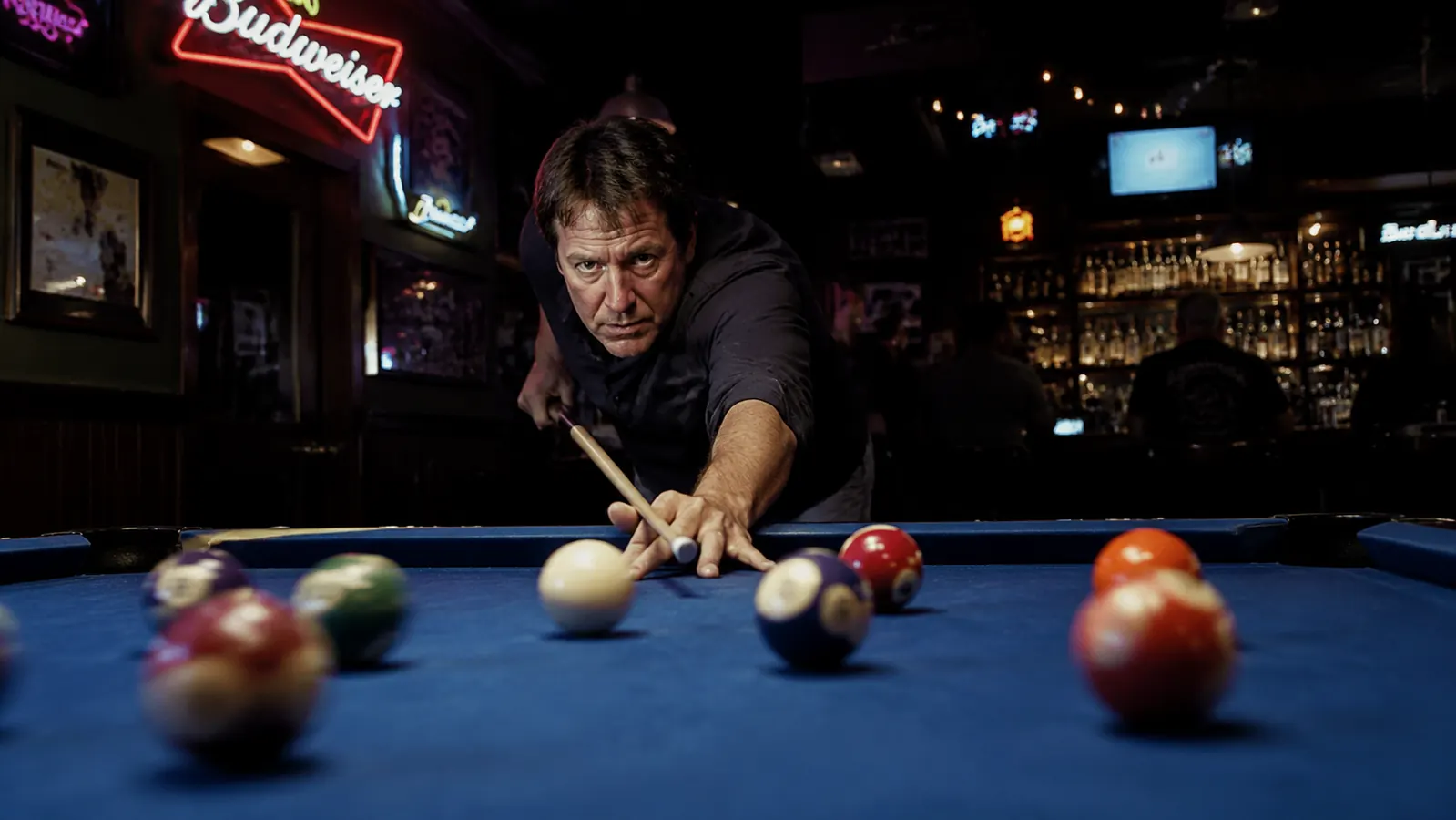 Pool player mid-break at a bar league table, cue extended at low angle, balls beginning to scatter