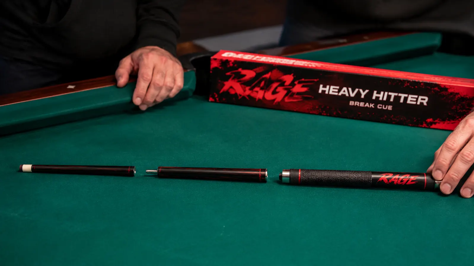 The three sections of a disassembled jump break cue laid out on a green felt surface, showing the joints and ferrule