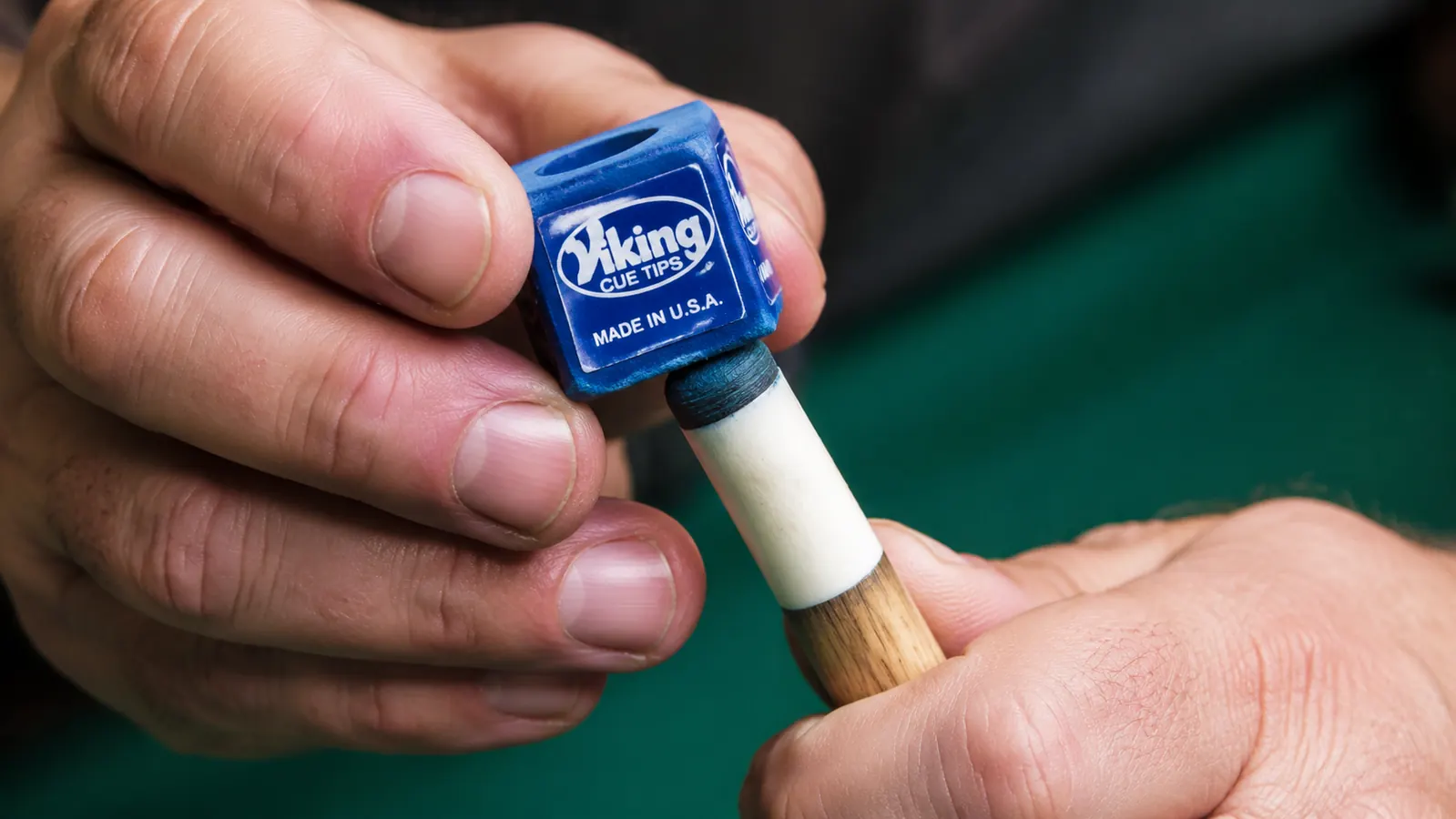 Close-up of a pool cue tip being chalked showing tip shape and ferrule condition
