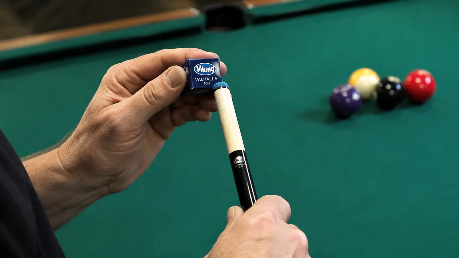 Close-up of a hand chalking a pool cue tip before a shot