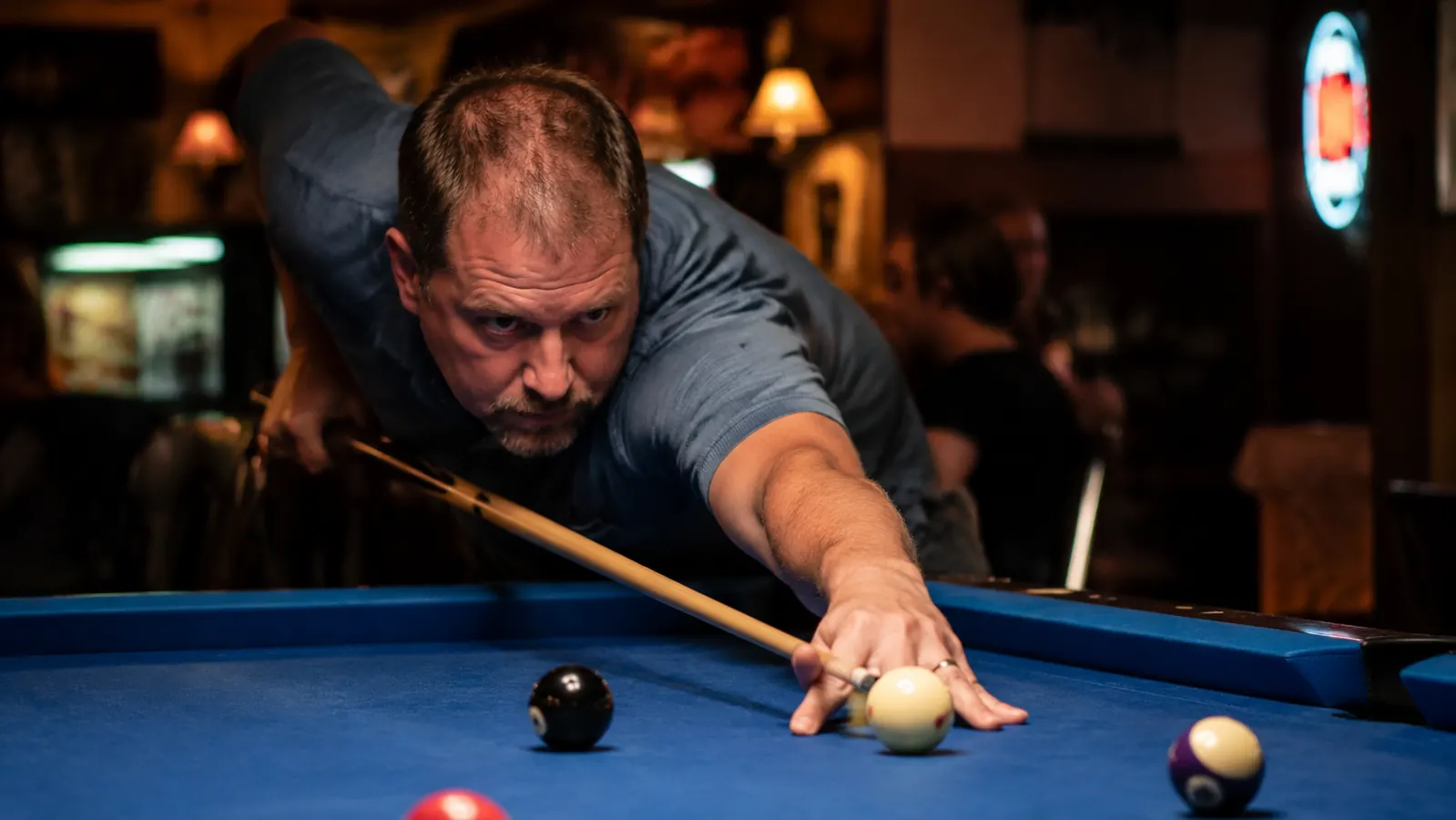 Player leaning over a pool table lining up a long position shot
